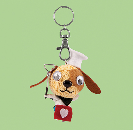 Cream string doll dog wearing red apron and a white chef's hat
